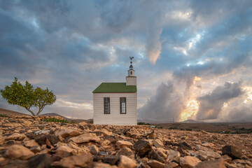 small cute white wooden chapel in a barren volcanic landscape. Sunset, landscape shot of the Ermita...