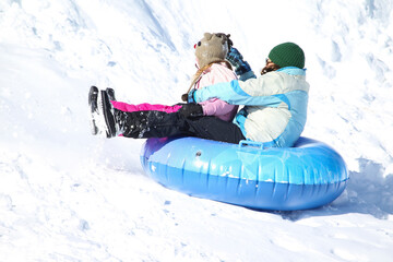 Mother and daughters playing in snow sledding