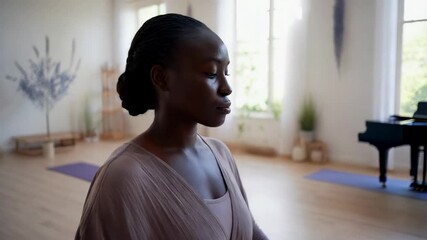A young Black woman engages in a mindfulness practice in a spacious studio filled with soft light and tranquility