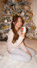 teenage girl with a xmas mug under the chtistmas tree