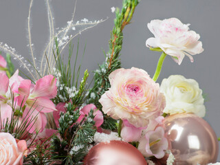 Close-up of Elegant Christmas Bouquet with Pink Flowers, Fir Branches, and Baubles on a Grey...