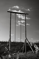 Naklejka premium Giant vintage wood swing in country landscape, sunset, art monochrome photo