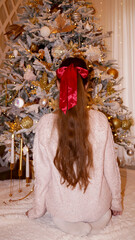 young girl with red ribbon in hair under the christmas tree