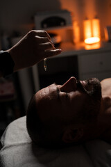 Oil is dripped onto a man's forehead for massage. Close up of a handsome man enjoying facial...