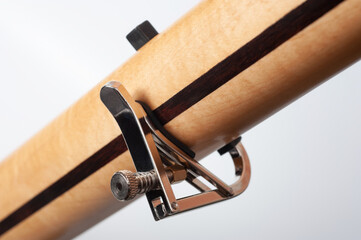 Six-string electric guitar, with a cream-colored wooden body, chrome fittings and capo.