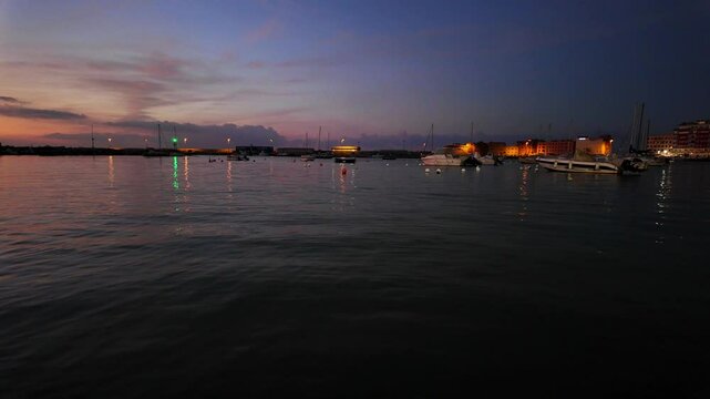 Anzio Italy Serene harbor at sunset with boats reflecting on calm water Scenic city lights illuminate the waterfront creating a peaceful atmosphere Ideal tourism travel coastal landscape