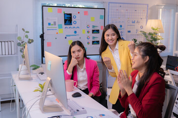 Two happy businesswomen celebrating their success while gazing at the computer screen, with a...