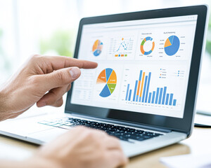 A person is pointing at a laptop screen with a pie chart on it