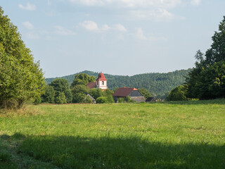 Summer view of old historical Bohemian village Zdirec Borejov with Church of St. James in in Baroque architectural style and green meadow and trees, Kokorin region, central Bohemia