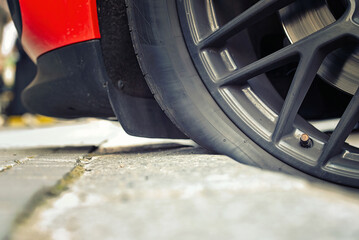 Car tire touching the curb in parking lot closeup. Automobile wheel parked nearcurb with the tire...