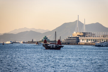Traditional Red-Sailed Junk Boat Sailing Across Victoria Harbour in Hong Kong