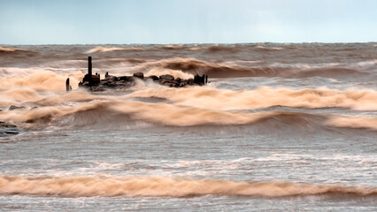 dramatic storm in the Baltic Sea, large waves crashing against the stone pier, blurred, unclear...