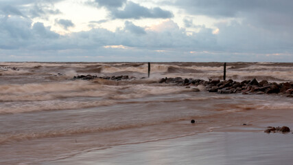 dramatic storm in the Baltic Sea, large waves crashing against the stone pier, blurred, unclear...