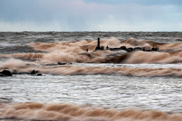 dramatic storm in the Baltic Sea, large waves crashing against the stone pier, blurred, unclear...