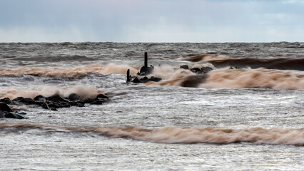 dramatic storm in the Baltic Sea, large waves crashing against the stone pier, blurred, unclear...