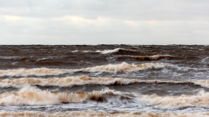 dramatic storm in the Baltic Sea, large waves crashing against the shore, blurred, unclear contours, rocky shore of Vidzeme