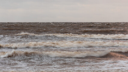 dramatic storm in the Baltic Sea, large waves crashing against the shore, blurred, unclear contours, rocky shore of Vidzeme