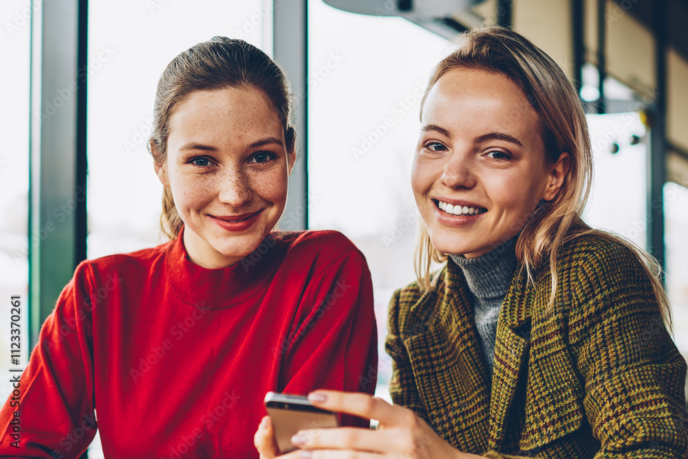 Poster portrait of two happy bloggers smiling at camera while discussing new funny application installed on