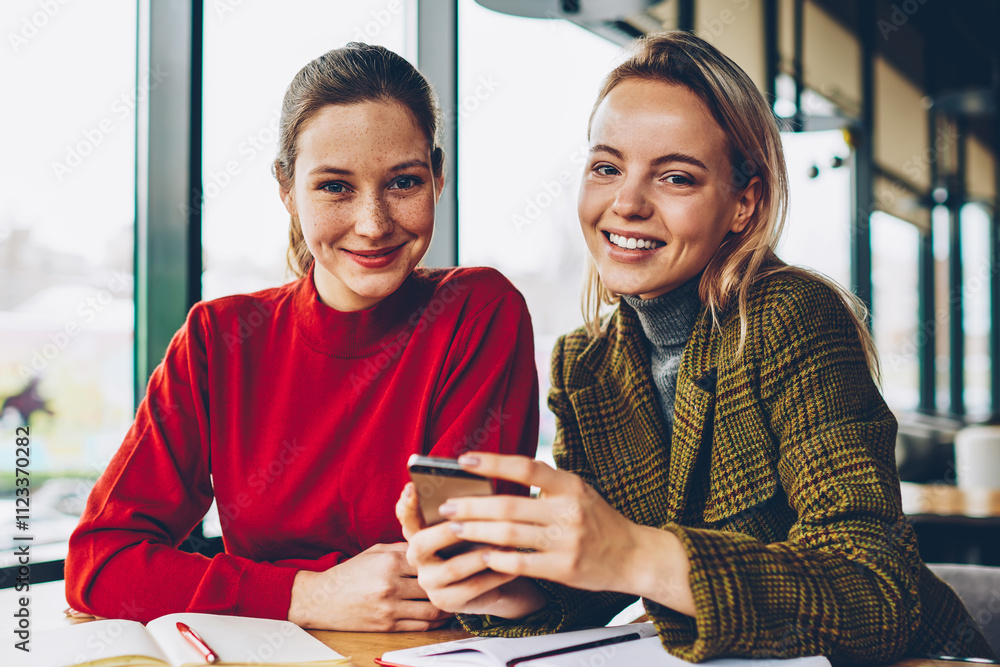 Poster portrait of two happy bloggers smiling at camera while discussing new funny application installed on