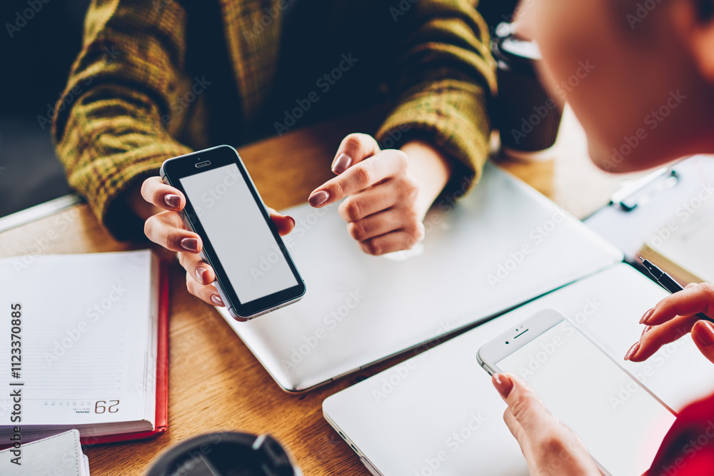 Poster cropped image of hipster girl showing application on smartphone with blank screen area to friend whi