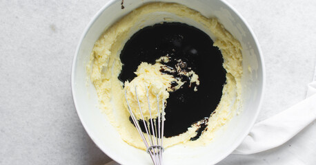Overhead view of molasses being added and whisked into creamed butter and sugar, top view of...
