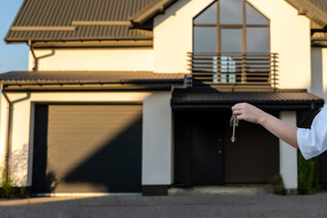 Hand holding a key in front of home. Leasing insurance and purchase concept. Real estate investment concept. Buying or renting