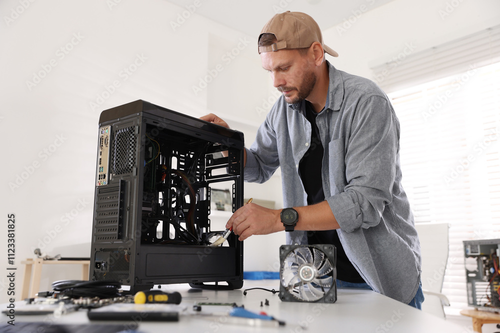 Poster man installing fan into computer at white table