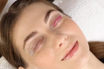 Woman undergoing eyelash laminating procedure in beauty salon, closeup