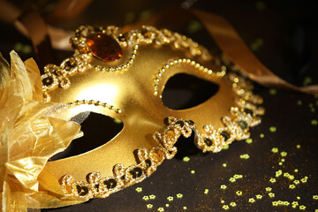 Beautiful carnival mask, ribbon and confetti on dark background, closeup