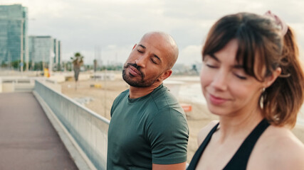 Close-up of an active healthy couple against the backdrop of seaside doing shoulder and neck warm-ups