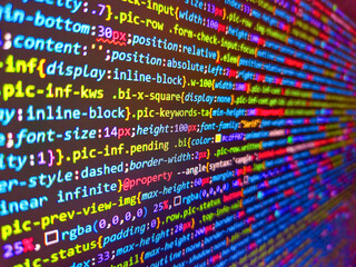 Closeup view of software code on a computer screen with blurred background words. Data encryption security code on a computer display. Structured sql code on monitor. Background image.
