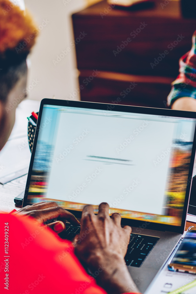 Poster cropped back view of african american young man keyboarding text on modern laptop device working on 