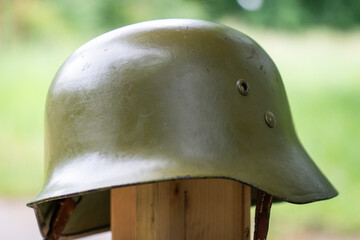 Old German World War I green military helmet on wooden stand