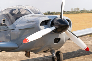 A gray military trainer propeller plane on a grassy airfield