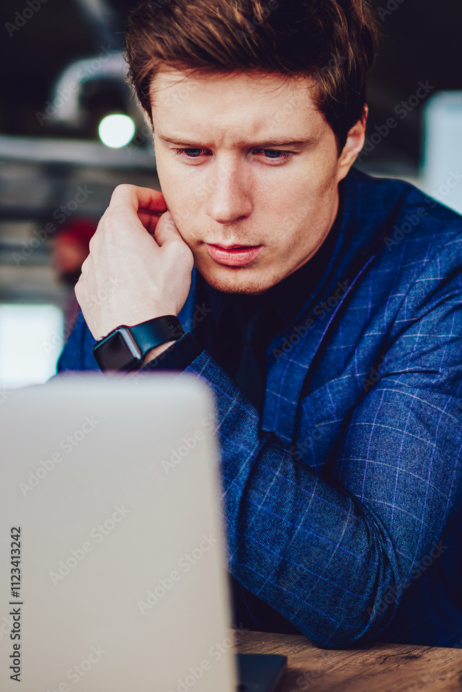 Poster puzzled caucasian male director of company searching information while browsing internet via modern 