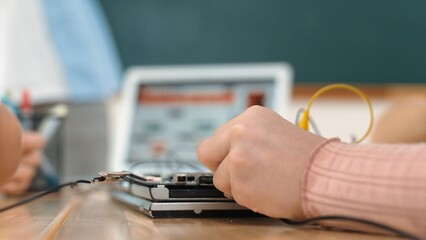 Closeup of student hands fixing main board while teacher teach engineering prompt and generated AI software program. Skilled children learning about artificial intelligence at stem class. Pedagogy.