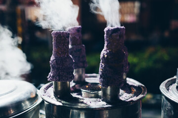 Cooking Puto bumbong, a popular Filipino delicacy of steamed purple rice cakes in sticky logs sold traditionally during Christmas season in night market. Selective focus.