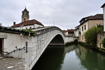 Fototapeta premium Charming Historic Bridge Over a Serene Waterway in a Quaint Italian Town