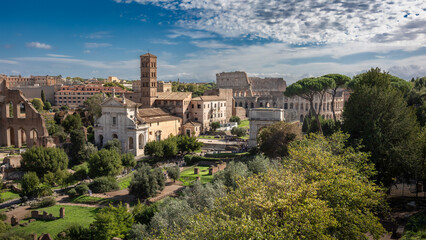 Panoramic aerial view of Foro Romano with ancient ruins and Colosseo on sunny day, Rome, Italy