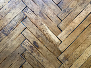Texture of old worn herringbone parquet floor, requiring repair, close up