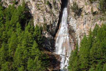 La Pisse waterfall and steep mountain slopes in Queyras Regional Natural Park. Ceillac. Summer in...
