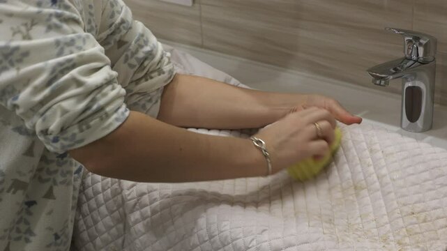 Woman removing dirt stains on light jacket. Female hand with sponge removing dirt stain on outerwear.