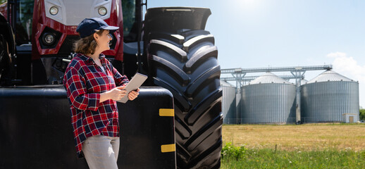 Female farmer with a digital tablet next to agricultural tractor