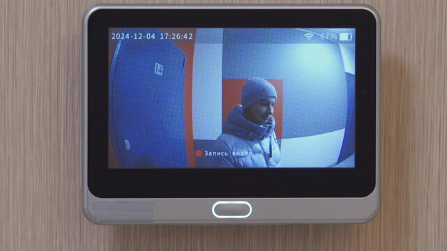 Woman ringing doorbell. Looking at screen of digital door peephole viewer. Smart peephole camera with display. Digital door viewer motion detection video doorbell for home.
