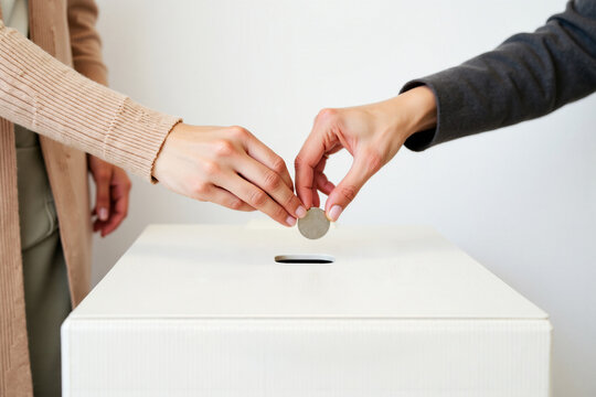 Two People Inserting Coins Into a Donation Box for Charity, fundraising