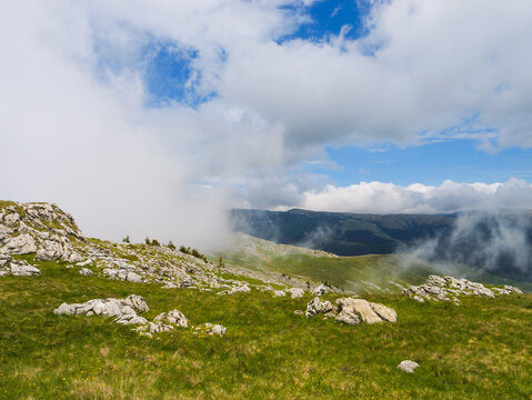 Rocks mountain landscape with yellow flowers and clouds passing between the rocks.