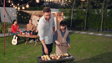 Family together in garden, father and daughter grill food for family member. Outdoor camping...