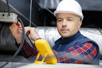electrician using a multimeter to test spotlight connections