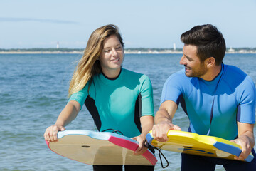 Obraz premium couple by the sea practicing position for bodyboarding
