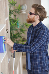 young blind man looking for a book on shelf
